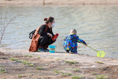 Photo for LUANNAN COUNTY, Hebei Province, China - March 22, 2020: A mother and son are playing by the water in the park. - Royalty Free Image