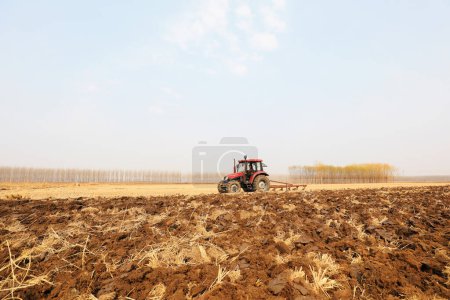 Photo for Farmers drive tractors to plow land in farmland, North China - Royalty Free Image