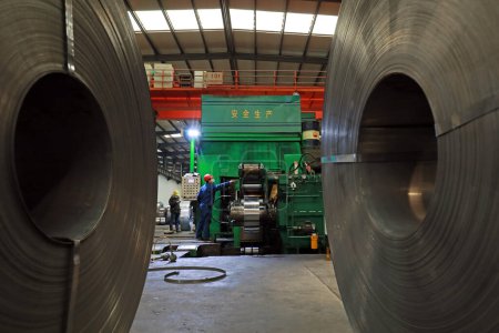 Foto de LUANNAN COUNTY, provincia de Hebei, China - 26 de marzo de 2020: Los trabajadores están ocupados en la línea de producción de tiras en una empresa de hierro y acero. - Imagen libre de derechos