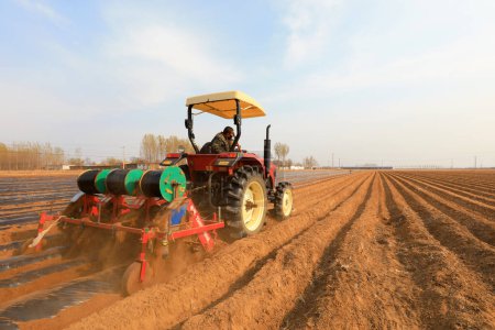 Foto de LUANNAN COUNTY, provincia de Hebei, China - 9 de abril de 2020: Los agricultores impulsan maquinaria agrícola para plantar batatas en los campos. - Imagen libre de derechos