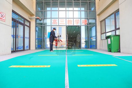 Téléchargez les photos : COMTÉ DE LUANNAN, province du Hebei, Chine - 13 avril 2020 : Les travailleurs utilisent des pulvérisateurs pour vaporiser du désinfectant dans une école, prévention de la nouvelle pneumonie par le coronavirus. - en image libre de droit