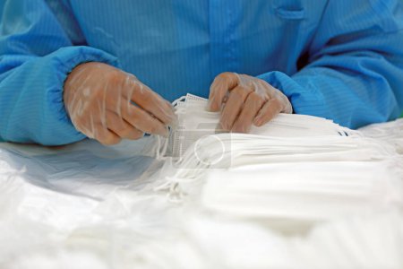 Foto de Los trabajadores están ocupados en la línea de producción en una fábrica de máscaras médicas. - Imagen libre de derechos