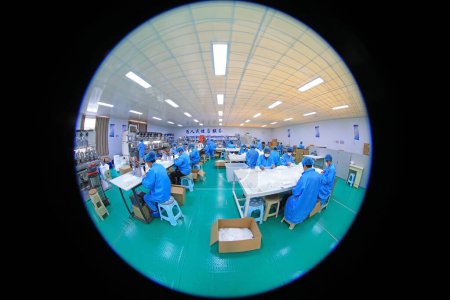 Foto de LUANNAN COUNTY, provincia de Hebei, China - 15 de abril de 2020: Los trabajadores están ocupados en la línea de producción en una fábrica de máscaras médicas. - Imagen libre de derechos