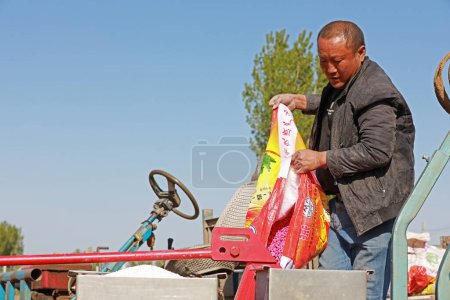 Foto de CONDADO DE LUANNAN, provincia de Hebei, China - 22 de abril de 2020: El agricultor agregó fertilizante al plantador en el campo. - Imagen libre de derechos