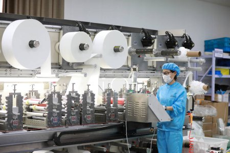 Foto de LUANNAN COUNTY, provincia de Hebei, China - 23 de abril de 2020: Los trabajadores están ocupados en la línea de producción en una fábrica de máscaras médicas. - Imagen libre de derechos