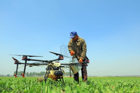 Foto de CONDADO DE LUANNAN, provincia de Hebei, China - 27 de abril de 2020: Un trabajador calificado está depurando el UAV agrícola, listo para rociar pesticidas. - Imagen libre de derechos