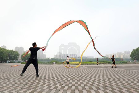 Foto de CONDADO DE LUANNAN, provincia de Hebei, China - 4 de agosto de 2020: La gente agita la seda de color para mantenerse en forma en el parque - Imagen libre de derechos