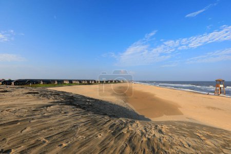 Téléchargez les photos : Maisons en bois et dunes de sable sur fond de ciel bleu - en image libre de droit