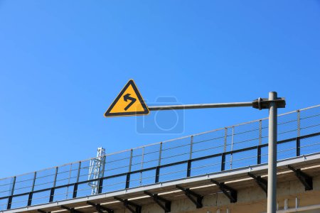 Foto de El signo de curva al lado del puente ferroviario está en el fondo del cielo azul - Imagen libre de derechos