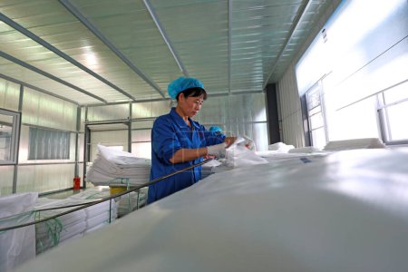 Foto de LUANNAN COUNTY, provincia de Hebei, China - 27 de septiembre de 2020: los trabajadores están ocupados en la línea de costura de bolsas de fibra - Imagen libre de derechos