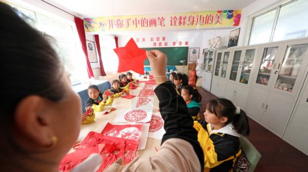 Téléchargez les photos : COMTÉ DE LUANNAN, Province du Hebei, Chine - 30 septembre 2020 : Les élèves du primaire apprennent l'art de couper le papier sous la direction des enseignants - en image libre de droit