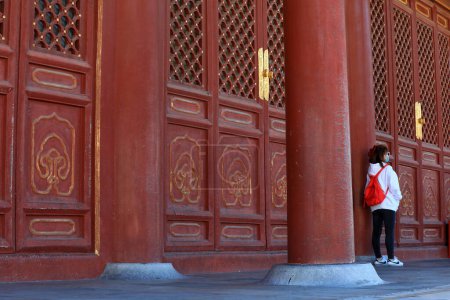 Foto de Una mujer juega fuera de una celosía ventana de madera en el templo del cielo, Beijing - Imagen libre de derechos