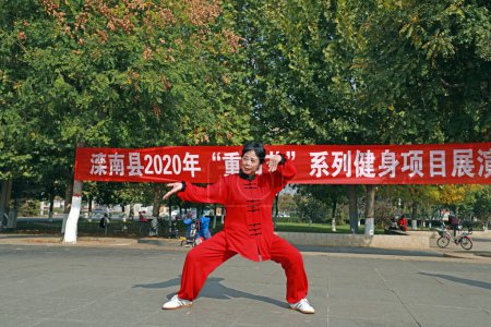 Téléchargez les photos : COMTÉ DE LUANNAN, Province du Hebei, Chine - 18 octobre 2020 : Une dame en rouge pratique le Taijiquan sur la place - en image libre de droit