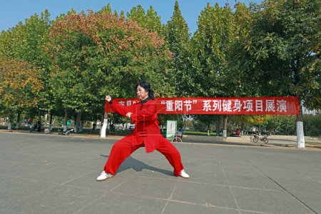 Photo for LUANNAN COUNTY, Hebei Province, China - October 18, 2020: A lady in red is practicing Taijiquan in the square - Royalty Free Image
