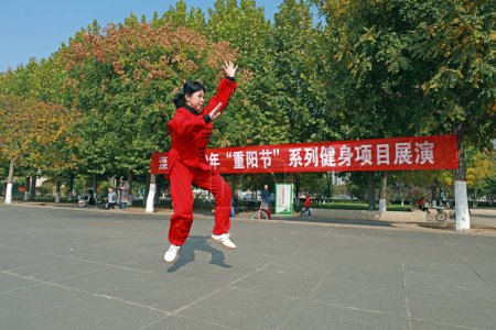 Photo for LUANNAN COUNTY, Hebei Province, China - October 18, 2020: A lady in red is practicing Taijiquan in the square - Royalty Free Image