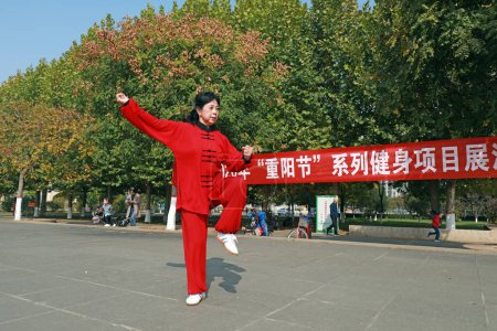 Foto de LUANNAN COUNTY, Provincia de Hebei, China - 18 de octubre de 2020: Una dama de rojo practica Taijiquan en la plaza - Imagen libre de derechos