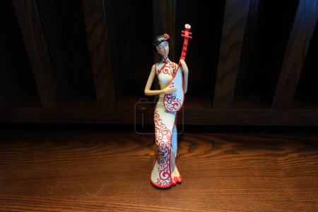 Téléchargez les photos : Une figure vêtue de cheongsam et embrassant des instruments de musique - en image libre de droit