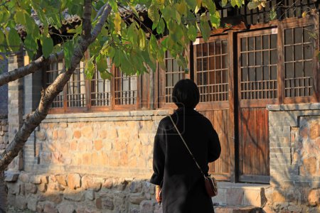 Photo for A lady's back is in front of an old house, China, - Royalty Free Image