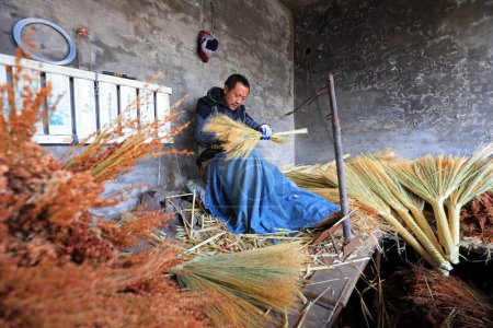 Foto de LUANNAN COUNTY, China - 11 de diciembre de 2020: los trabajadores hacen grandes escobas en un taller, LUANNAN COUNTY, provincia de Hebei, China - Imagen libre de derechos