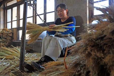 Photo for LUANNAN COUNTY, China - December 11, 2020: workers make big broomsticks in a workshop, LUANNAN COUNTY, Hebei Province, China - Royalty Free Image