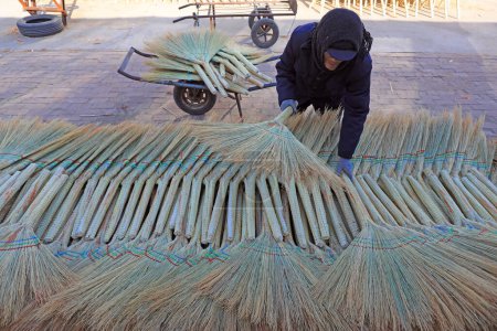 Photo for LUANNAN COUNTY, China - December 11, 2020: The worker is drying the big broom in a workshop, LUANNAN COUNTY, Hebei Province, China - Royalty Free Image