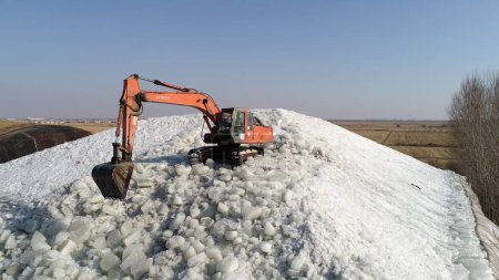 Foto de LUANNAN COUNTY, Provincia de Hebei, China - 22 de enero de 2021: excavadoras empacan hielo en pilas de hielo en una bodega de hielo. - Imagen libre de derechos