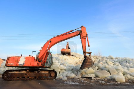 Foto de LUANNAN COUNTY, Provincia de Hebei, China - 22 de enero de 2021: excavadoras empacan hielo en pilas de hielo en una bodega de hielo - Imagen libre de derechos
