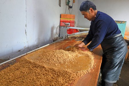 Foto de CONDADO DE LUANNAN, provincia de Hebei, China - 26 de enero: los hogares de procesamiento de dulces crujientes de maní están mezclando harina de maní y azúcar granulada en talleres familiares. - Imagen libre de derechos