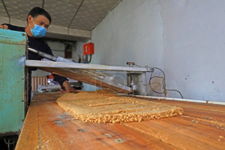 Photo for LUANNAN COUNTY, Hebei Province, China - January 26: peanut crunchy candy processing households in rolling, peanut flour and sugar thin in a family workshop. - Royalty Free Image