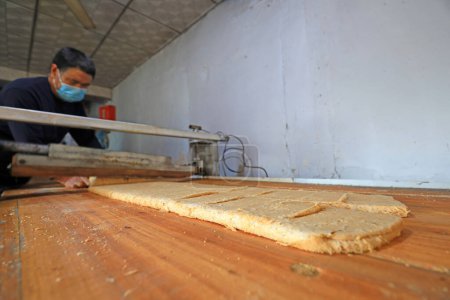 Téléchargez les photos : COMTÉ DE LUANNAN, province du Hebei, Chine - 26 janvier : ménages de transformation de bonbons croquants d'arachides en rouleaux, farine d'arachide et sucre mince dans un atelier familial. - en image libre de droit