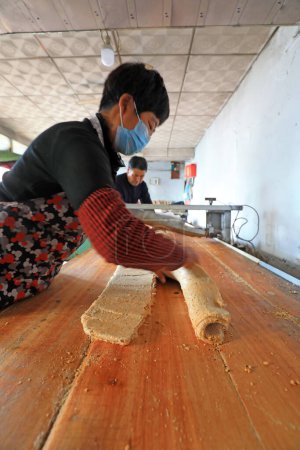 Téléchargez les photos : COMTÉ DE LUANNAN, province du Hebei, Chine - 26 janvier : ménages de transformation de bonbons croquants d'arachides en rouleaux, farine d'arachide et sucre mince dans un atelier familial. - en image libre de droit