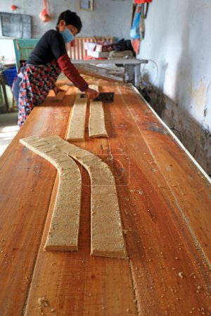 Foto de CONDADO DE LUANNAN, provincia de Hebei, China - 26 de enero: hogares de procesamiento de dulces crujientes de maní en laminado, harina de maní y azúcar delgada en un taller familiar. - Imagen libre de derechos