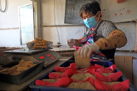 Téléchargez les photos : COMTÉ DE LUANNAN, province du Hebei, Chine - 26 janvier : Les ménages de transformation emballent des bonbons croquants aux arachides dans un atelier familial. - en image libre de droit