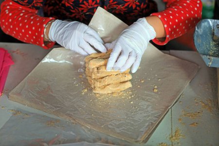 Téléchargez les photos : Les ménages de transformation emballent des bonbons croquants aux arachides dans un atelier familial. - en image libre de droit