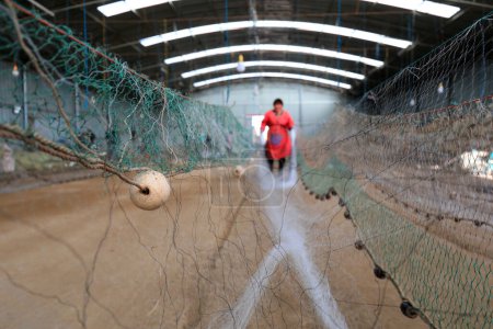 Foto de LUANNAN COUNTY, China - 10 de marzo de 2020: trabajadores que cosen redes de pesca para pesquerías marinas, LUANNAN COUNTY, Hebei Province, China - Imagen libre de derechos