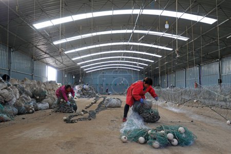 Téléchargez les photos : COMTÉ DE LUANNAN, Chine - 10 mars 2020 : travailleurs cousant des filets de pêche pour la pêche maritime, COMTÉ DE LUANNAN, province du Hebei, Chine - en image libre de droit