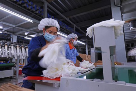Photo for LUANNAN COUNTY - February 2, 2020: women workers busy in the production line of nitrile protective gloves, LUANNAN COUNTY, Hebei Province, China - Royalty Free Image