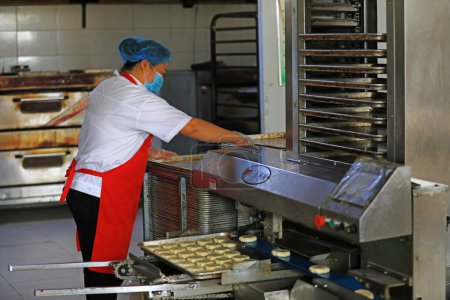 Photo for LUANNAN COUNTY, Hebei Province, China - September 27, 2020: Workers on the moon cake production line work hard in the food processing plant - Royalty Free Image