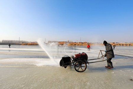 Photo for LUANNAN COUNTY, Hebei Province, China - January 22, 2021: Farmers use electric saws to cut river ice in the wild - Royalty Free Image