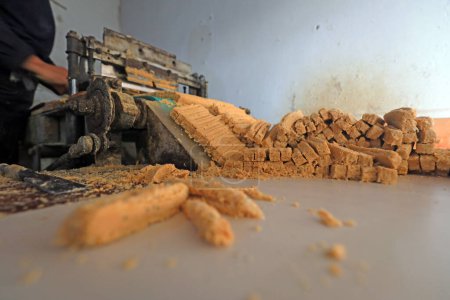 Verarbeitende Haushalte produzieren mit Maschinen in einer Familienwerkstatt Erdnuss-Knusperbonbons.
