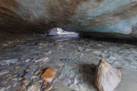 Téléchargez les photos : Entrée d'une grotte de glace creusée dans le glacier Vallelunga traversée par un ruisseau. Le glacier recule rapidement en raison du réchauffement climatique, Alto Adige, Italie - en image libre de droit