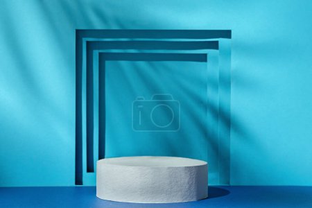 Téléchargez les photos : Blue background with shadow and light and podium pedestal cylinder for showing and demonstrating the product and promoting it with copy space. High quality illustration - en image libre de droit