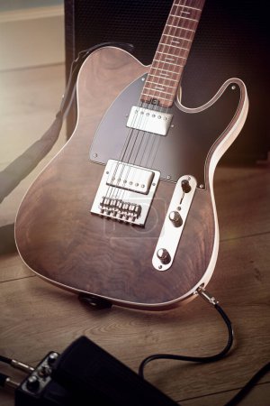 Foto de Primer plano en el cuerpo de la guitarra eléctrica personalizada con acabado natural, se apoya contra amplificador, pedal en primer plano, bengalas de lente - Imagen libre de derechos