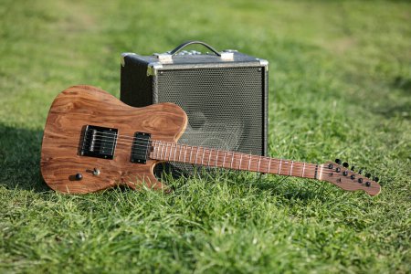 Téléchargez les photos : Guitare électrique et amplificateur à l'extérieur sur l'herbe verte fraîche - en image libre de droit