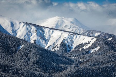 Foto de Picos de montaña cubiertos de nieve en las nubes - Imagen libre de derechos