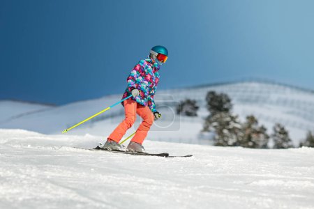 Foto de Joven esquiadora deslizándose por la ladera en un día soleado en una estación de montaña. - Imagen libre de derechos