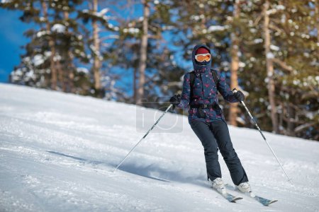 Foto de Amateur esquiadora hembra deslizándose por la ladera en un día soleado en una estación de montaña. - Imagen libre de derechos