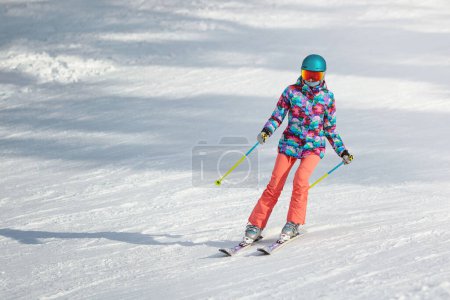 Téléchargez les photos : Jeune skieuse apprenant à glisser sur la pente par une journée ensoleillée dans une station de montagne. Espace de copie. - en image libre de droit