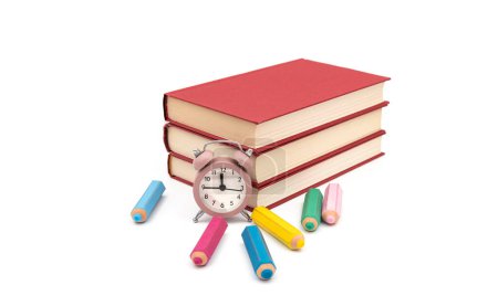 Foto de Clásico reloj de mesa rosa con libros rojos y borrador de colores en forma de lápiz sobre fondo blanco - Imagen libre de derechos