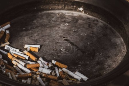 Foto de Restos de cigarrillos exprimidos en un cenicero - Imagen libre de derechos